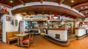 Um espaço de bar rústico com vigas de madeira, um balcão com diversas garrafas e uma placa que indica 'DIFFERENT BEER'.