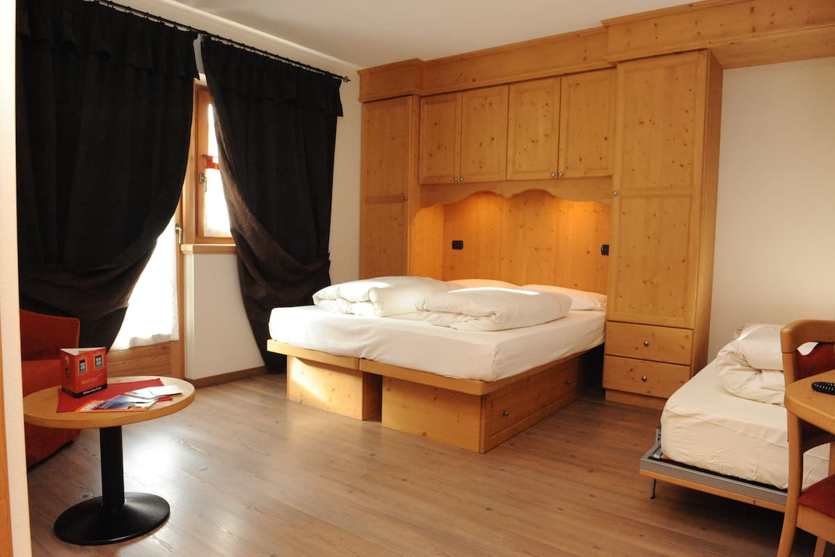A bedroom with a wooden bed, a small table, and a wardrobe.