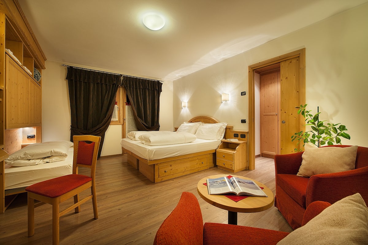 A hotel room with a bed, a desk, a chair, a sofa, and a small table.