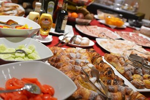 A buffet with various food items including pastries, fruits, and vegetables.