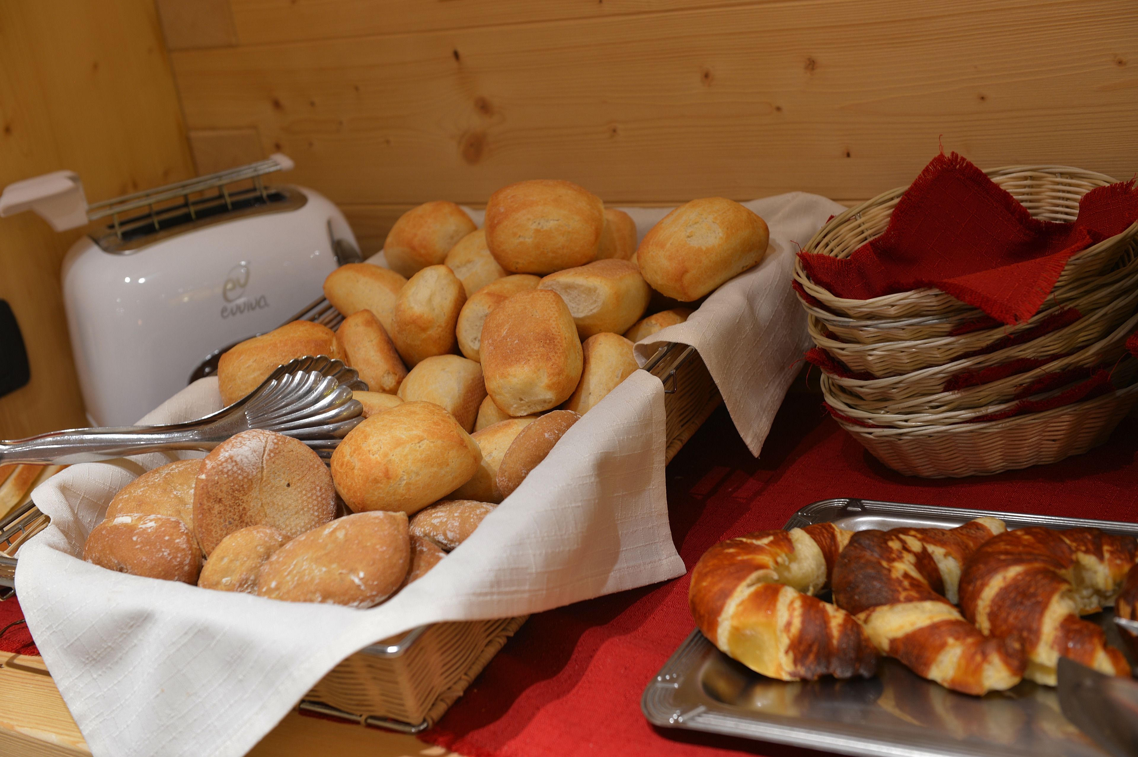 Una mesa de buffet con panes y pasteles varios, un tostador y utensilios para servir.