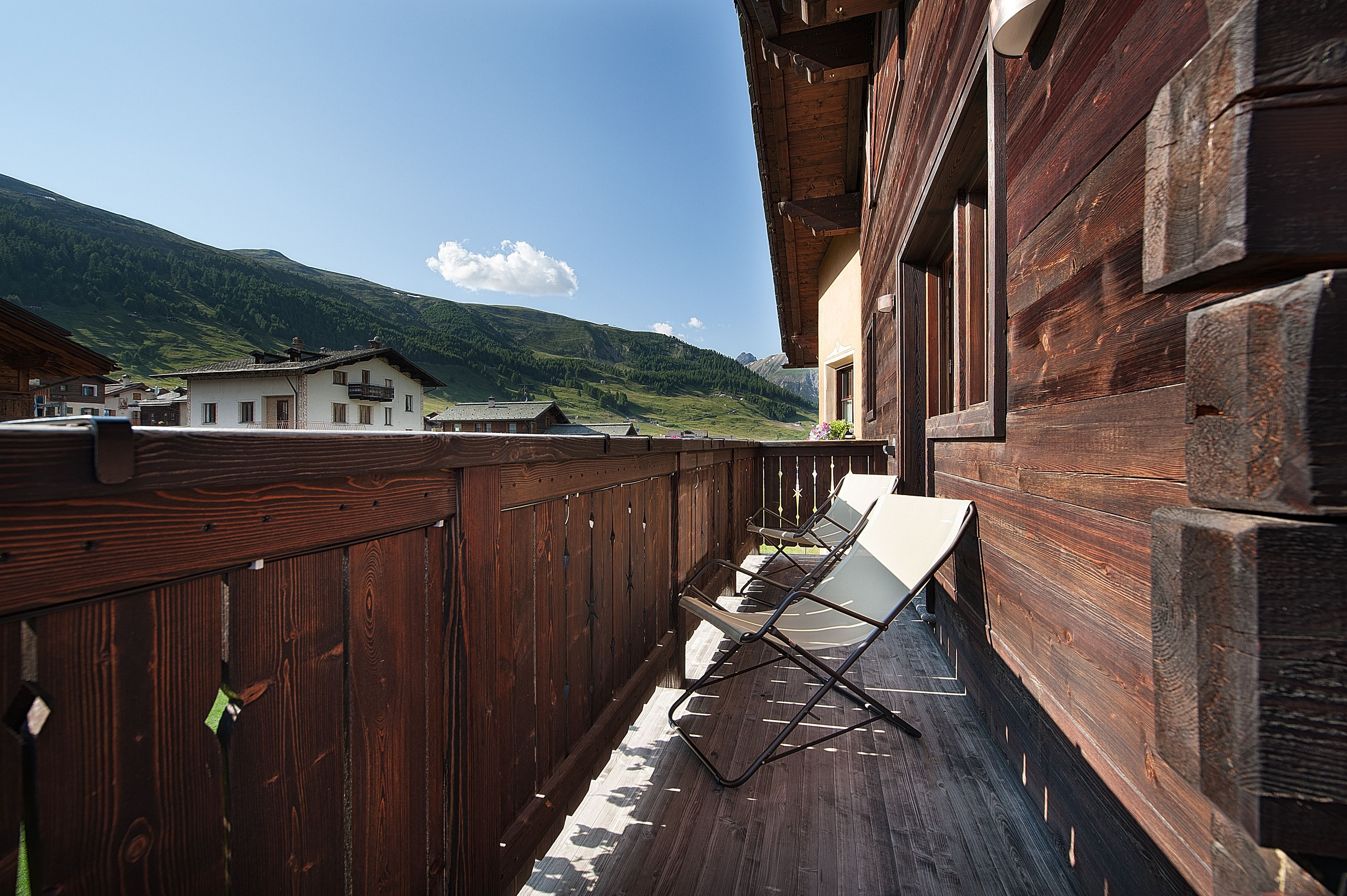 Un balcon en bois offrant une vue sur un paysage montagneux.