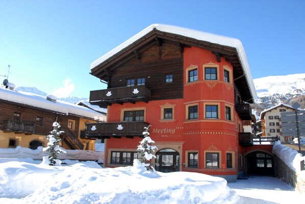 A red building with balconies and a sign that reads "Meeting Hotel." - Hotel Meeting (Livigno)