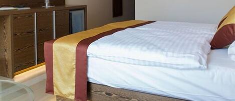 Ein Schlafzimmer mit einem Bett, einer Holzkommode, einem Glastisch und einem Bild an der Wand.