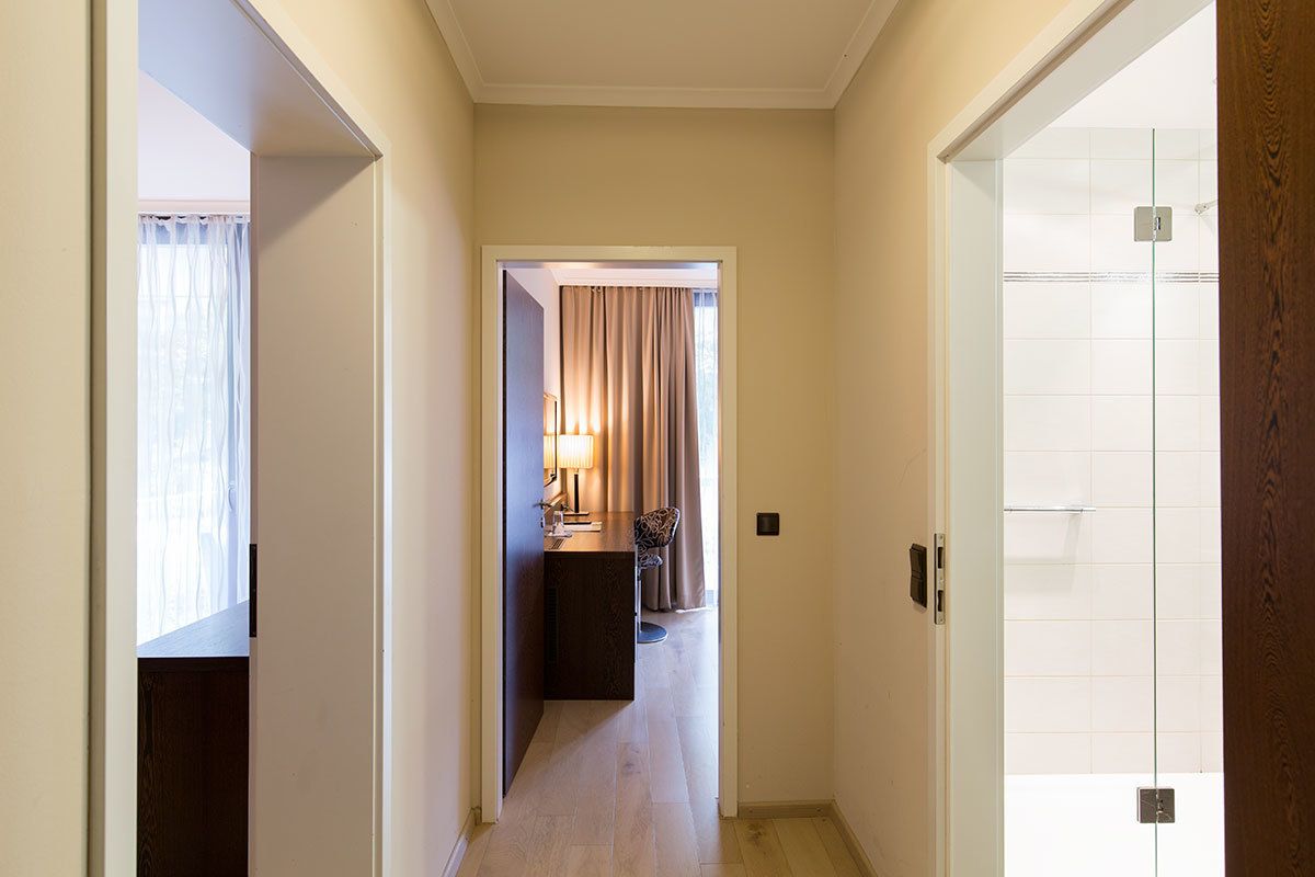Un pasillo estrecho que conduce a un baño con ducha y un pequeño rincón de descanso con mesa y silla.