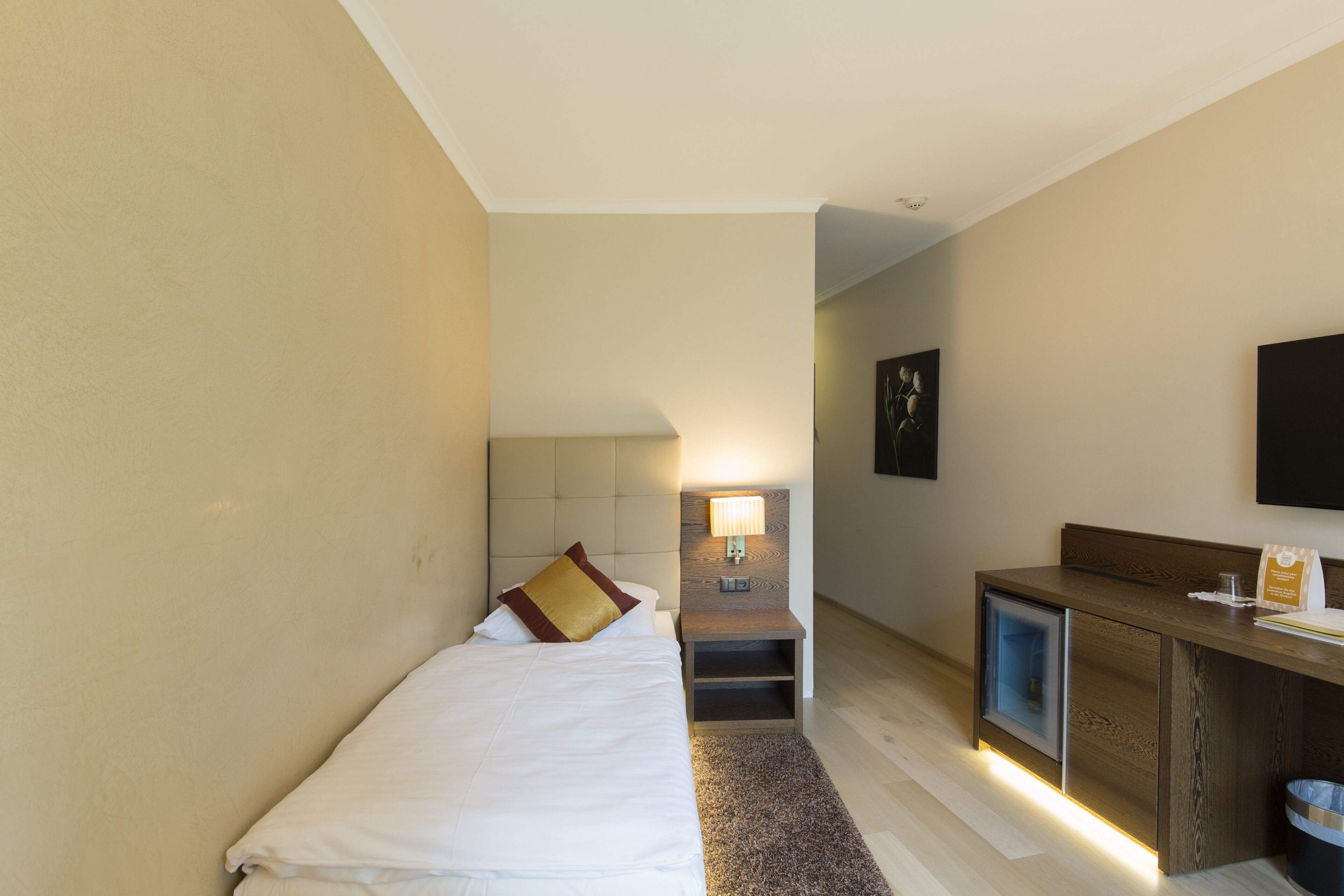 Une chambre d’hôtel avec un lit, un bureau, une lampe et un téléviseur.