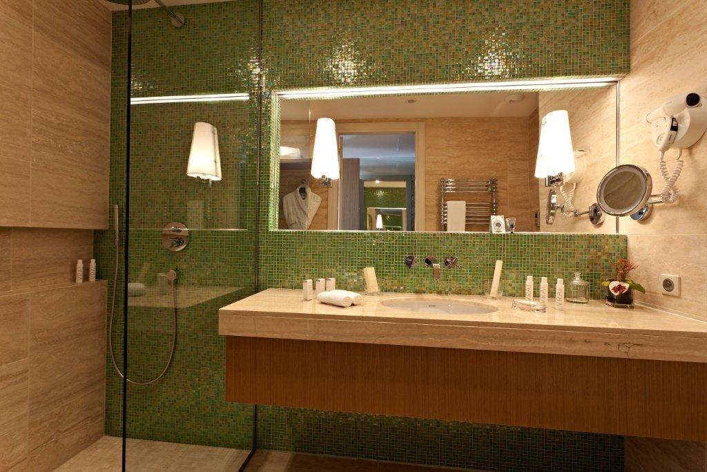 A bathroom with a large mirror, two sinks, a shower, and a towel rack.