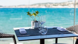 A table set with a folded towel, two wine glasses, and a small vase with green plants, overlooking a body of water. - Hostellerie La Farandole (Sanary-sur-Mer)