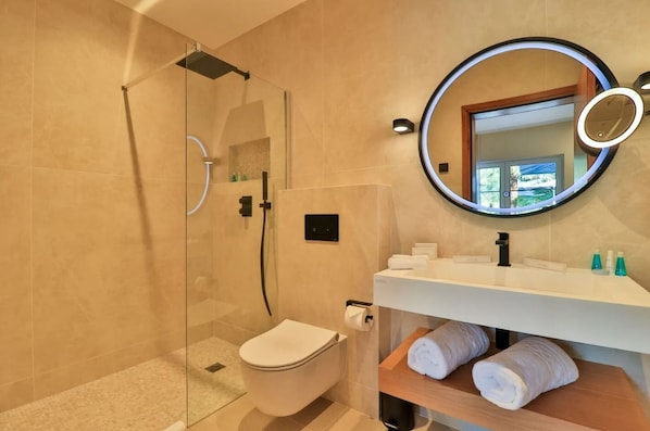 A modern bathroom with a glass-enclosed shower, a toilet, a sink with a mirror, and a towel rack. - Hostellerie La Farandole (Sanary-sur-Mer)