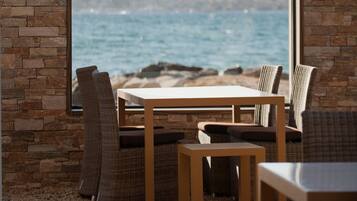 Un espacio de descanso con vista al mar, que incluye una pared de piedra y muebles de mimbre.