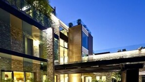 A modern building with a glass facade, outdoor wooden deck, and a stone-textured wall. - Hostellerie La Farandole (Sanary-sur-Mer)