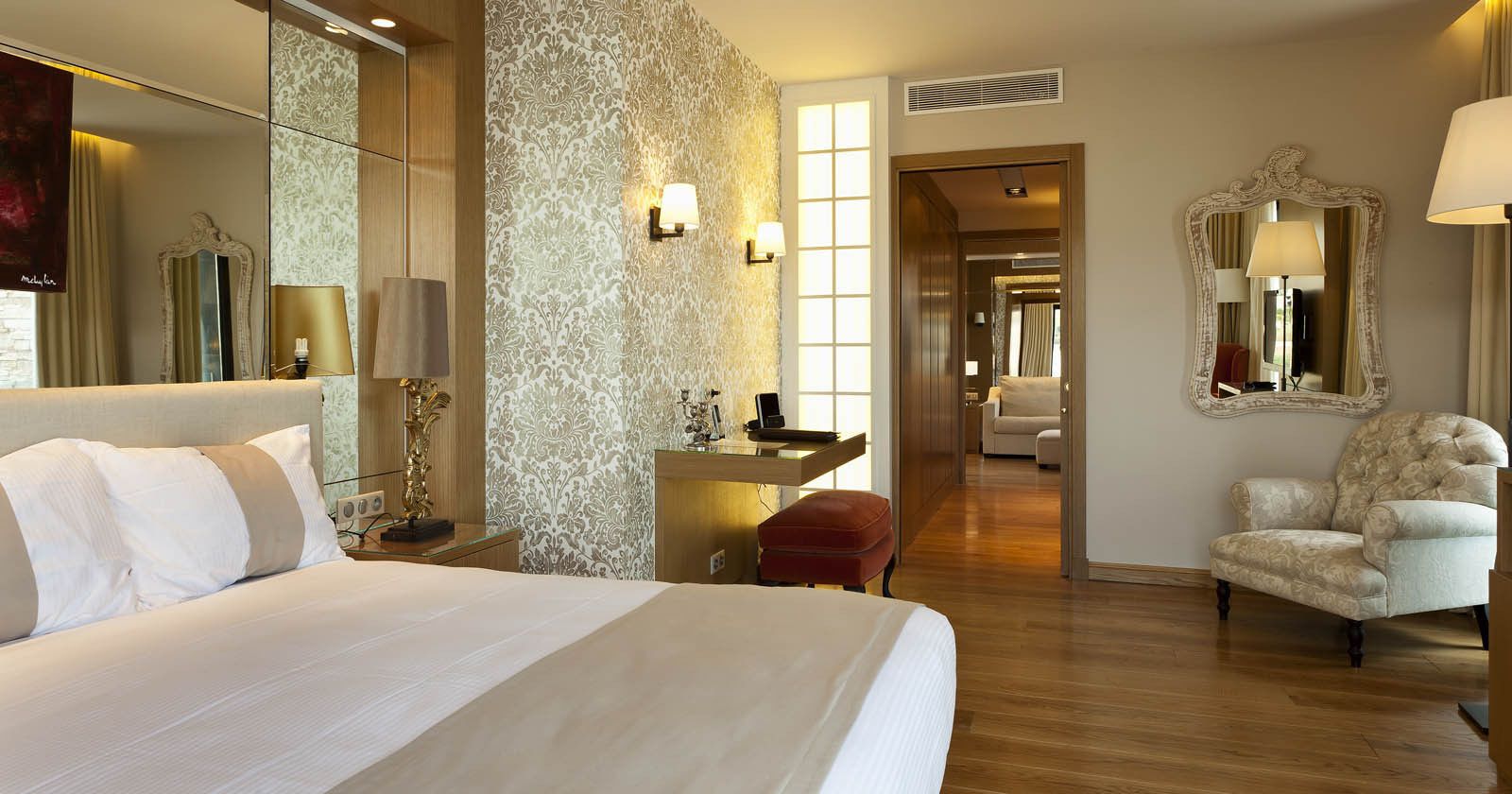 Una habitación de hotel con una cama grande, un escritorio, una silla y un espejo.