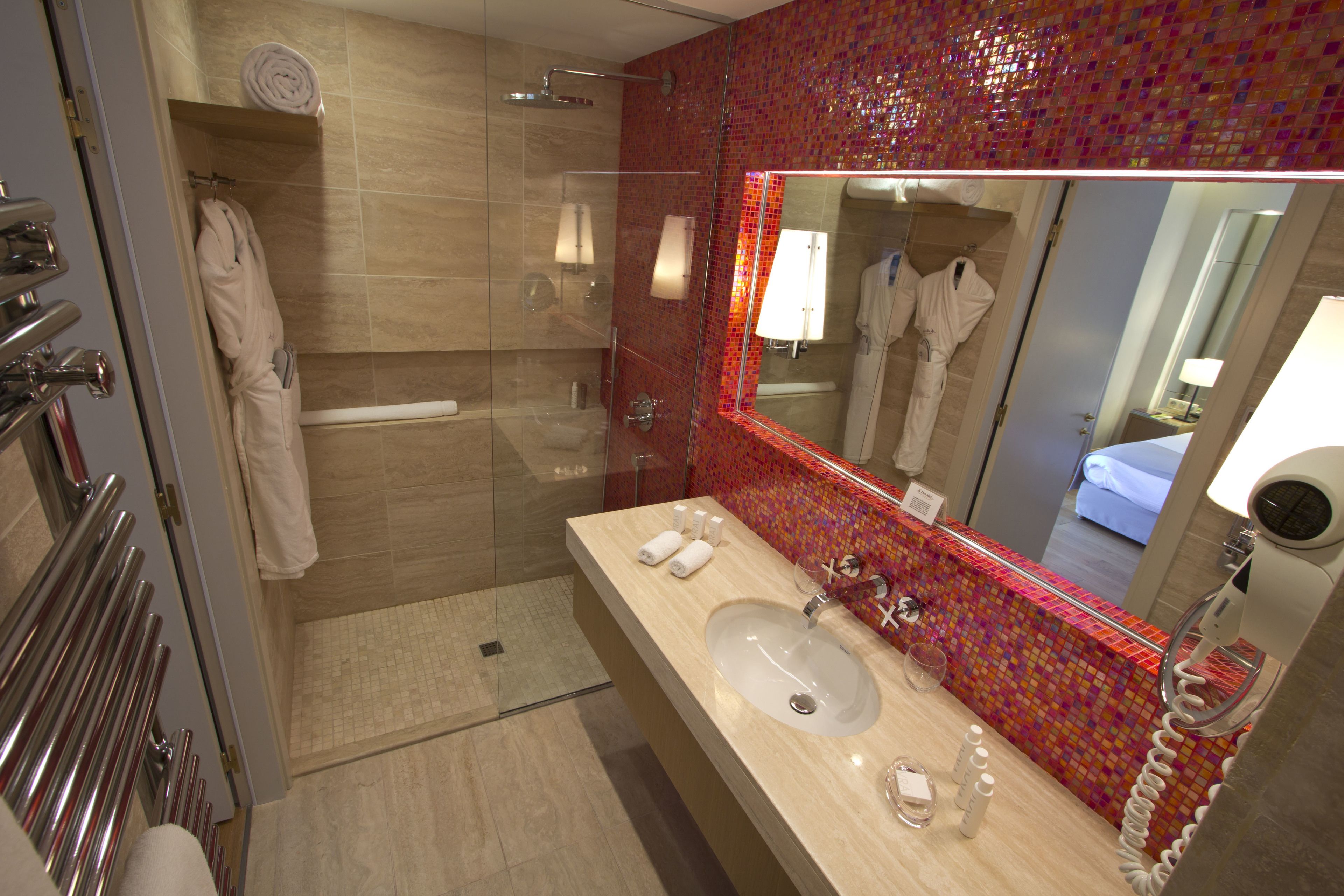 A modern bathroom with a large mirror, a sink, and a shower area.