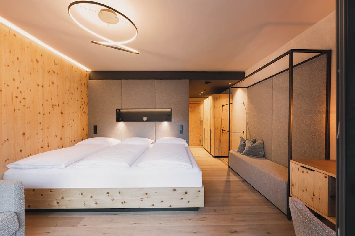 Ein modernes Schlafzimmer mit einem hölzernen Bett, einer eingebauten Bank und einem an der Wand montierten Fernseher.