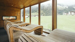 Un sauna avec des bancs en bois et de grandes fenêtres donnant sur un paysage verdoyant.