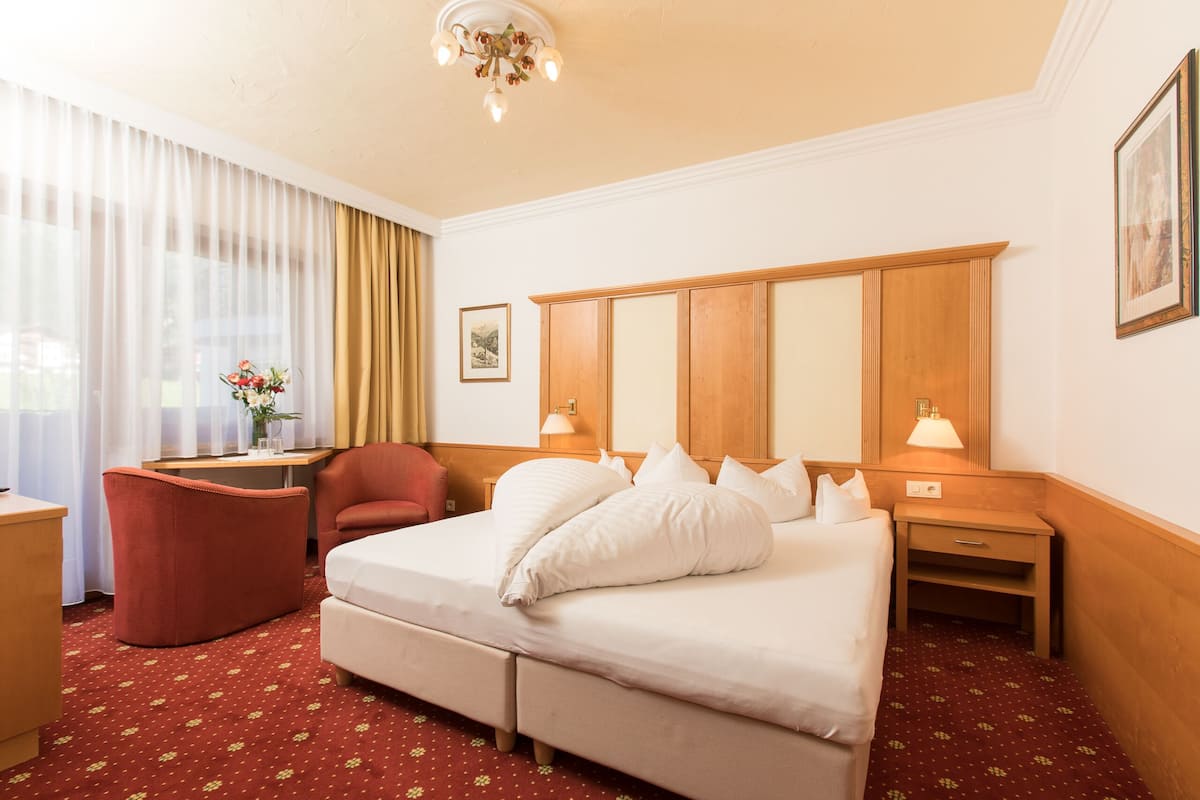 Ein Hotelzimmer mit einem großen Bett, einem Schreibtisch, einem Sessel und einem Nachttisch.