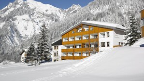 Ein mehrstöckiges Hotel mit Holzfassade in einer verschneiten Berglandschaft.