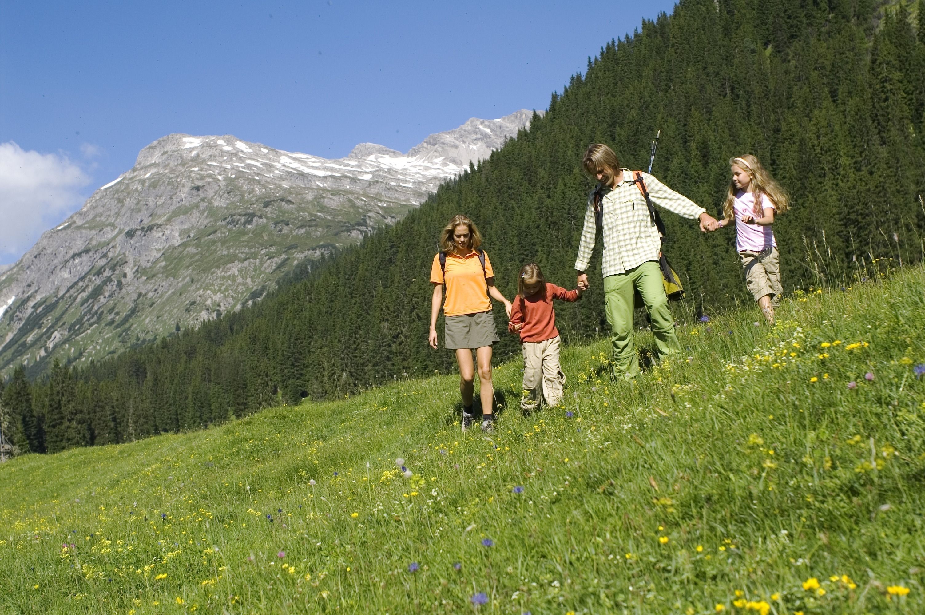 A family hiking on a grassy hillside with a mountain in the background.