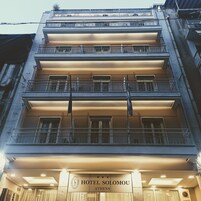 Um hotel de vários andares com varandas e uma placa com a inscrição "HOTEL SOLOMONOU ATHENS".