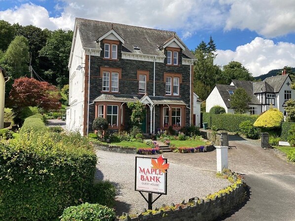 A two-story guest house with a stone facade, a well-maintained garden, and a sign indicating it is a Maple Bank guest house. - Maple Bank (Keswick)