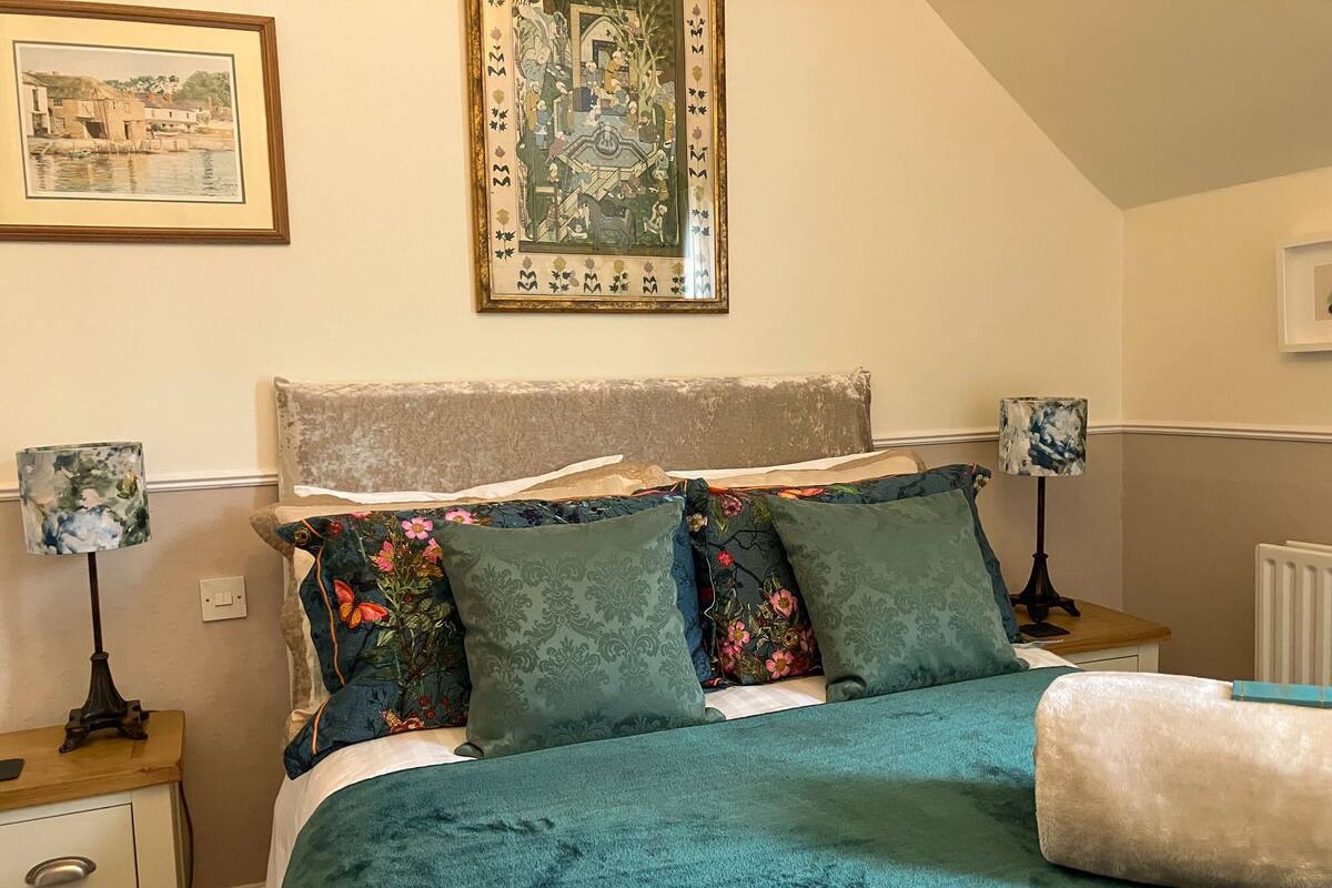 A bedroom with a bed, two nightstands, a radiator, and two wall-mounted lamps.