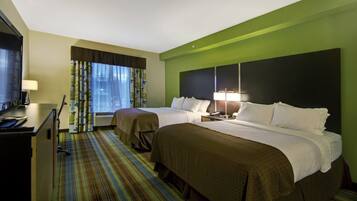 A hotel room with two beds, a desk, a TV, and a window with curtains.