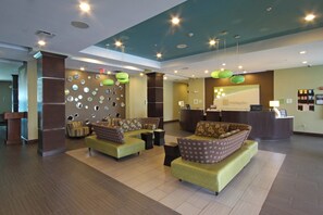 A hotel lobby with a reception desk, seating area with sofas, and a wall decorated with circular mirrors.