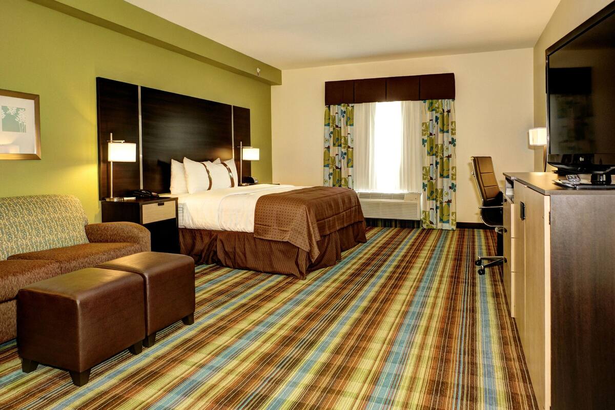A hotel room with a bed, a sofa, a desk, and a television.