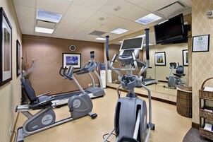 Un gimnasio equipado con cintas de correr, bicicletas estáticas y una máquina de remo.