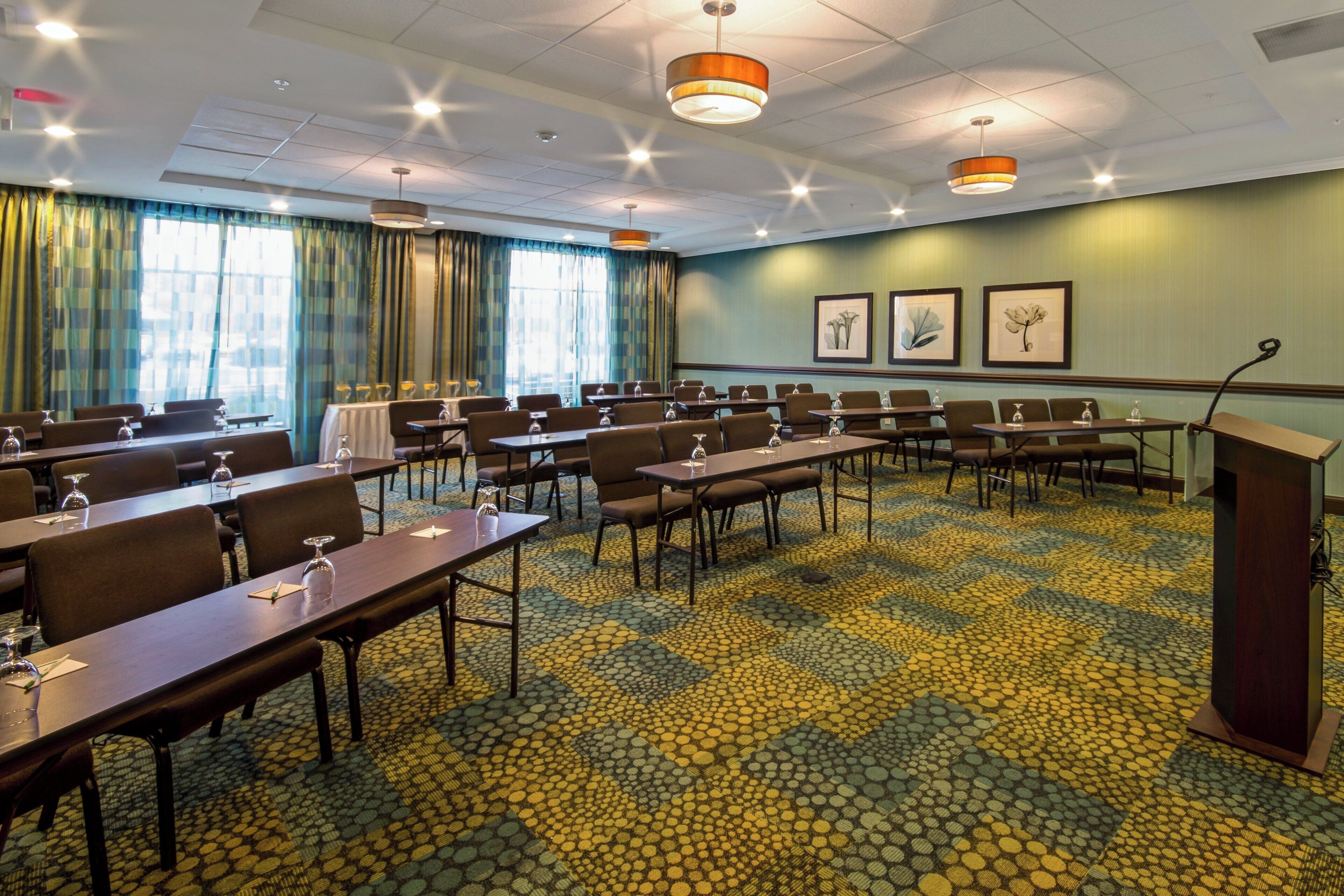 A conference room with tables and chairs, a podium, and framed artwork on the wall.