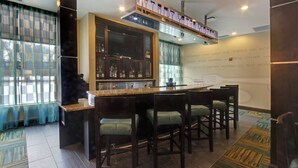 Una zona de bar con barra, taburetes y un expositor de botellas.
