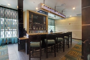 A bar area with a counter, stools, and a display cabinet with bottles.