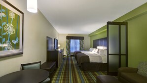 A hotel room with a bed, two bedside tables, a desk, a chair, a sofa, and a TV.