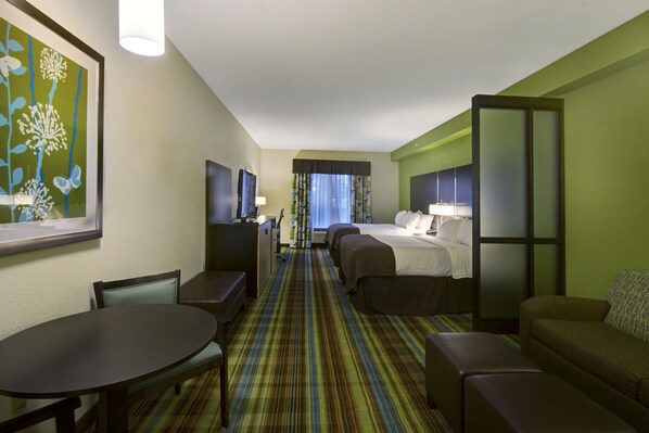 Habitación de hotel con cama, dos mesitas de noche, escritorio, silla, sofá y televisor.