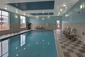 Una piscina interior con piso a cuadros, sillas y un letrero de salvavidas.