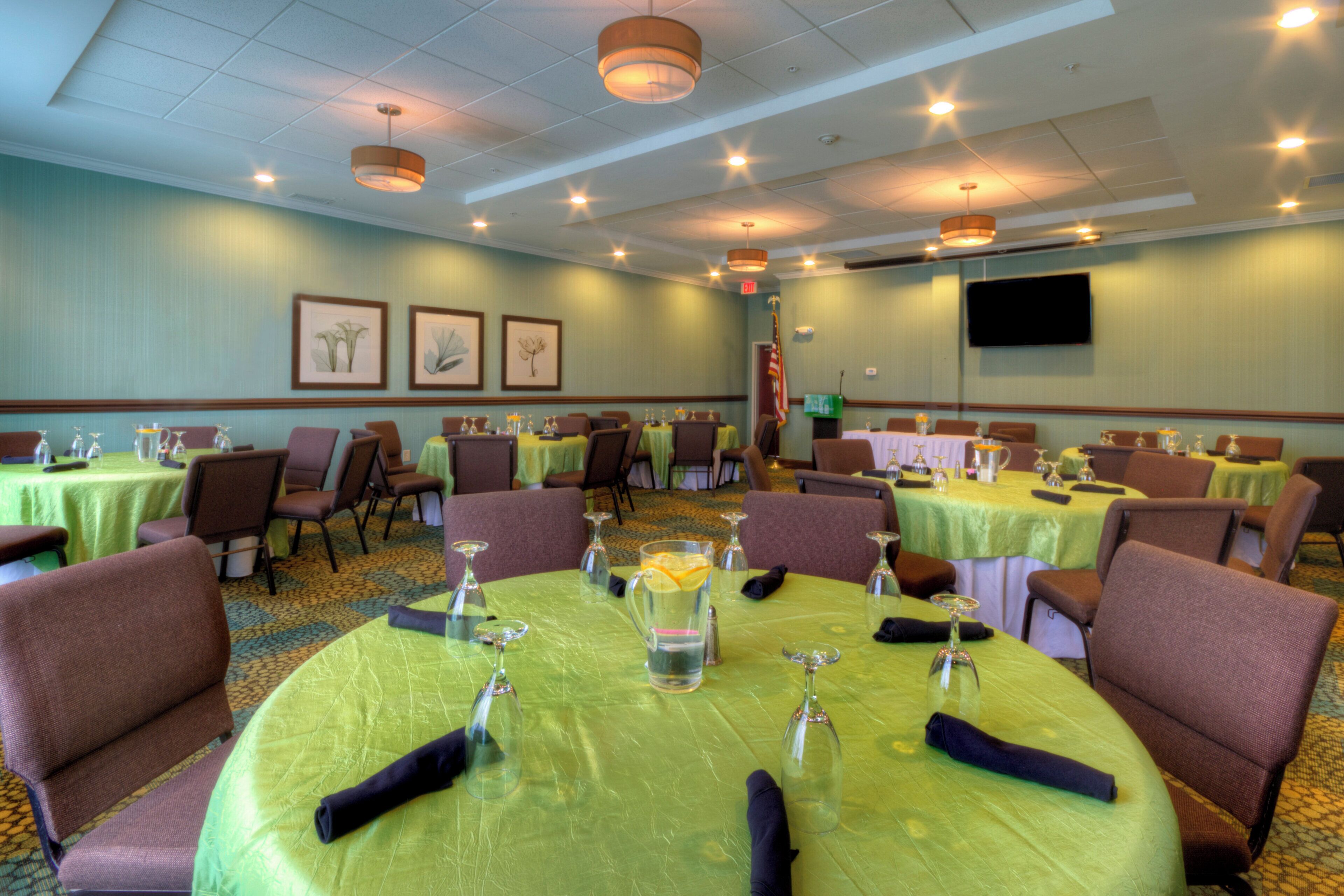 A conference room with round tables, chairs, and framed botanical artwork on the walls.