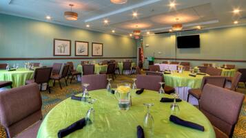A conference room with round tables, chairs, and framed botanical artwork on the walls.