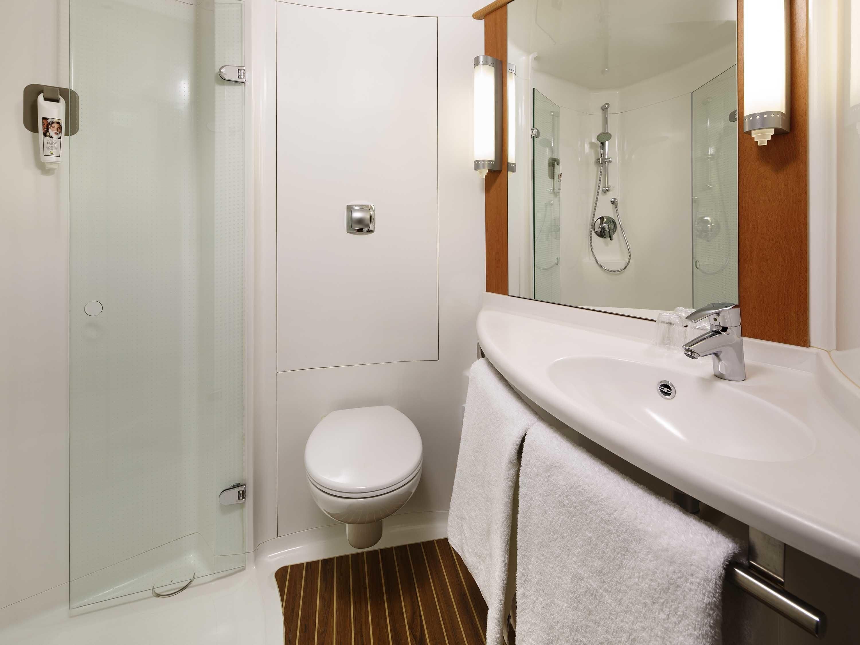 Un baño con ducha, inodoro, lavabo y un perchero para toallas.