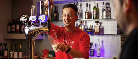 A bartender pouring a drink from a tap with multiple beer options.
