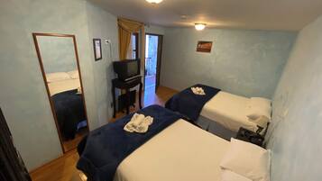 A hotel room with two beds, a desk with a television, and a mirror.