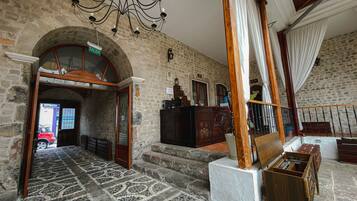 A lobby with a stone wall, a chandelier, a staircase, and a reception desk.