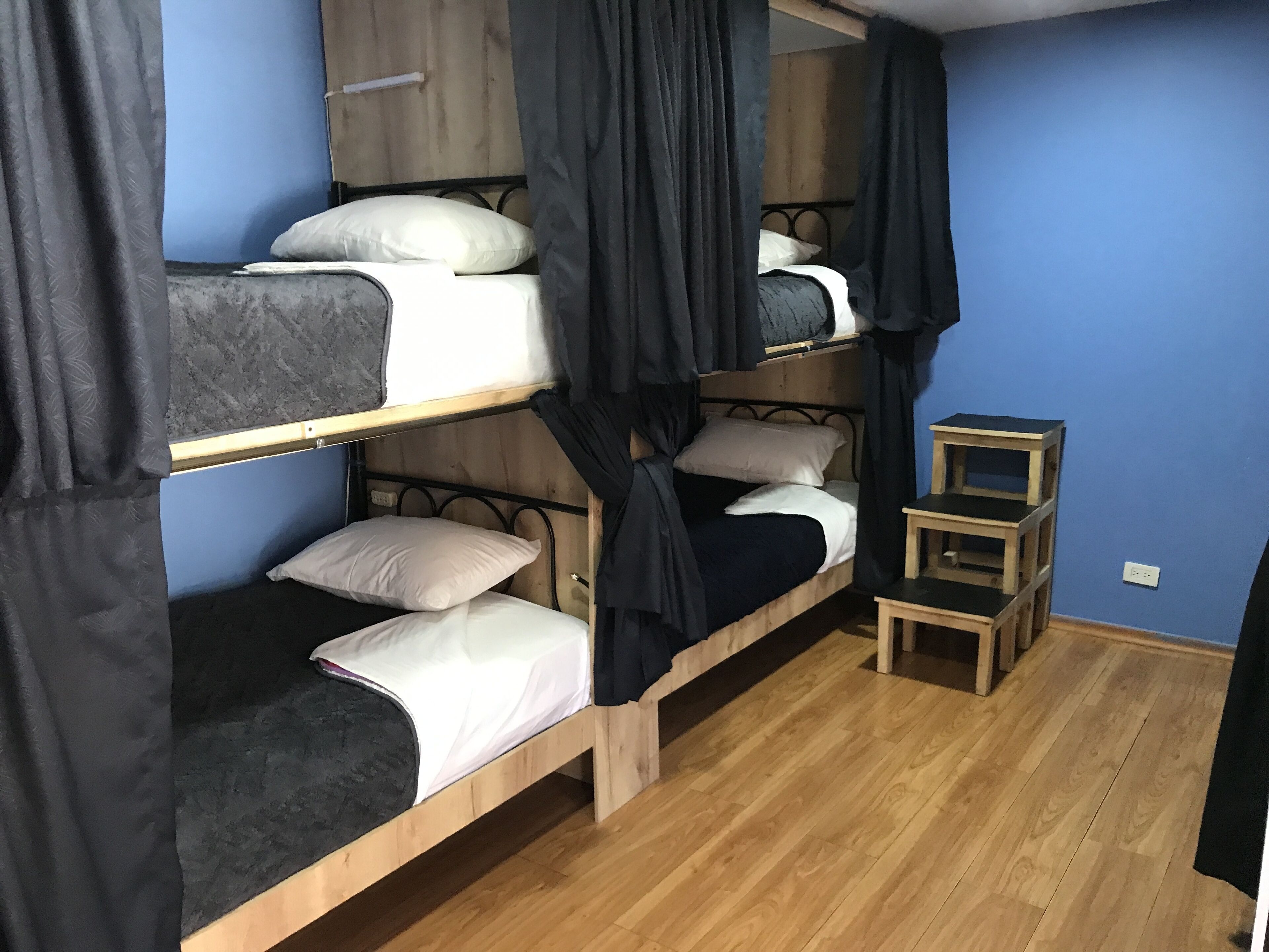 Un dormitorio con literas, una mesita de madera y una cortina.