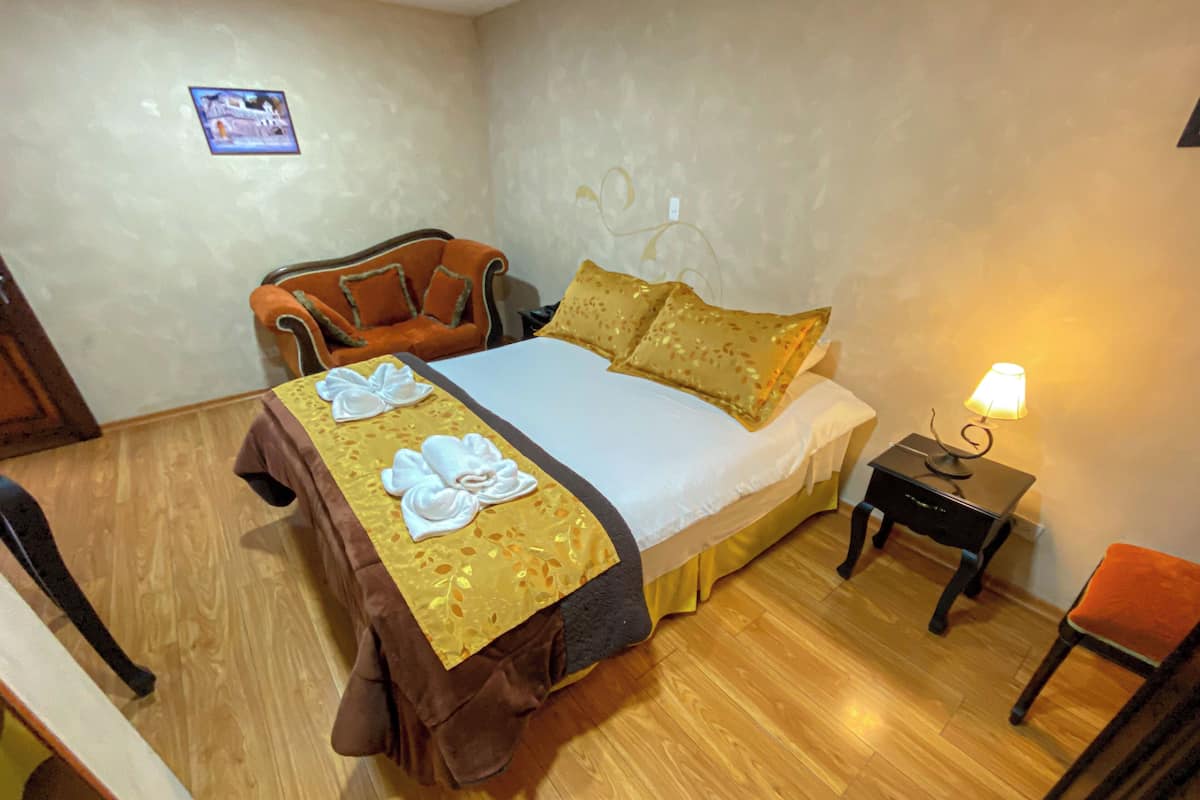 Una cama bien hecha con una colcha blanca y marrón, dos almohadas y una mesita de noche con una lámpara.