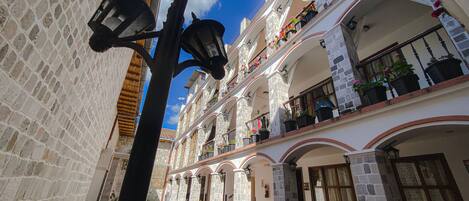 Un patio con piso de baldosas, paredes de piedra y una farola.