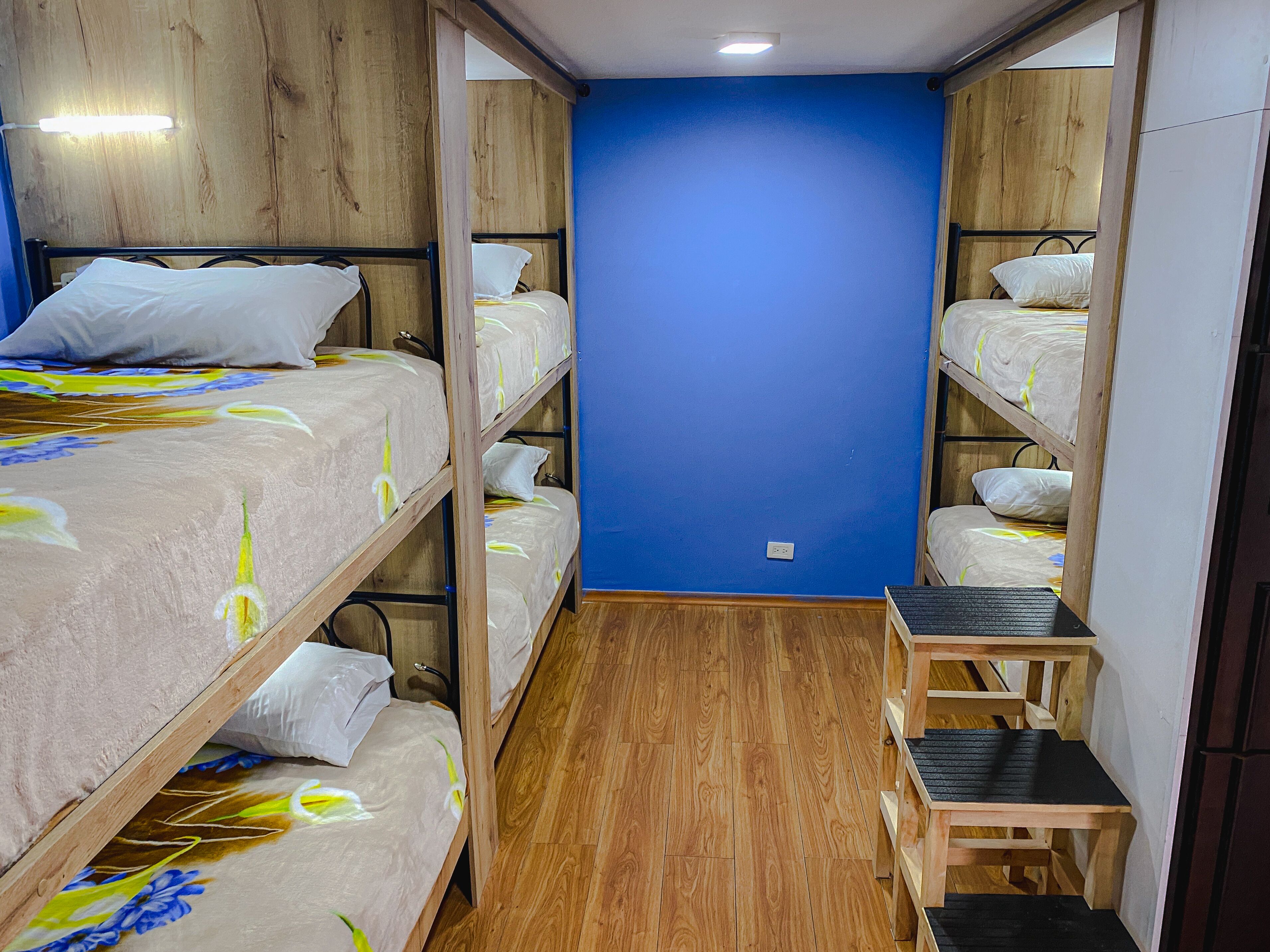 Une chambre de dortoir avec des lits superposés, une petite table en bois et un mur bleu.