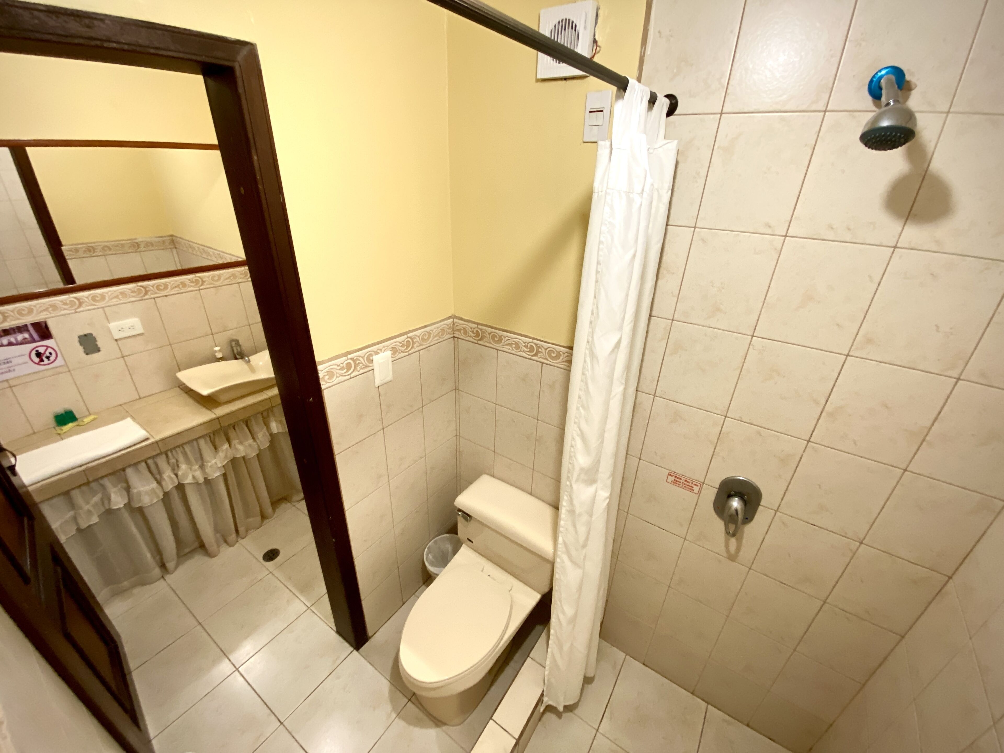 Un baño pequeño con inodoro, lavamanos y ducha.