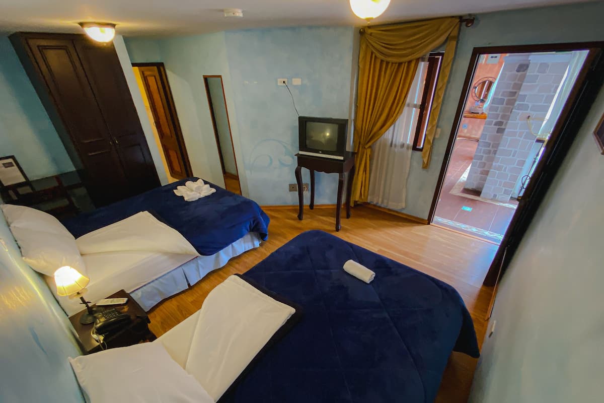 Una habitación de hotel con dos camas, televisión y una pequeña mesa.