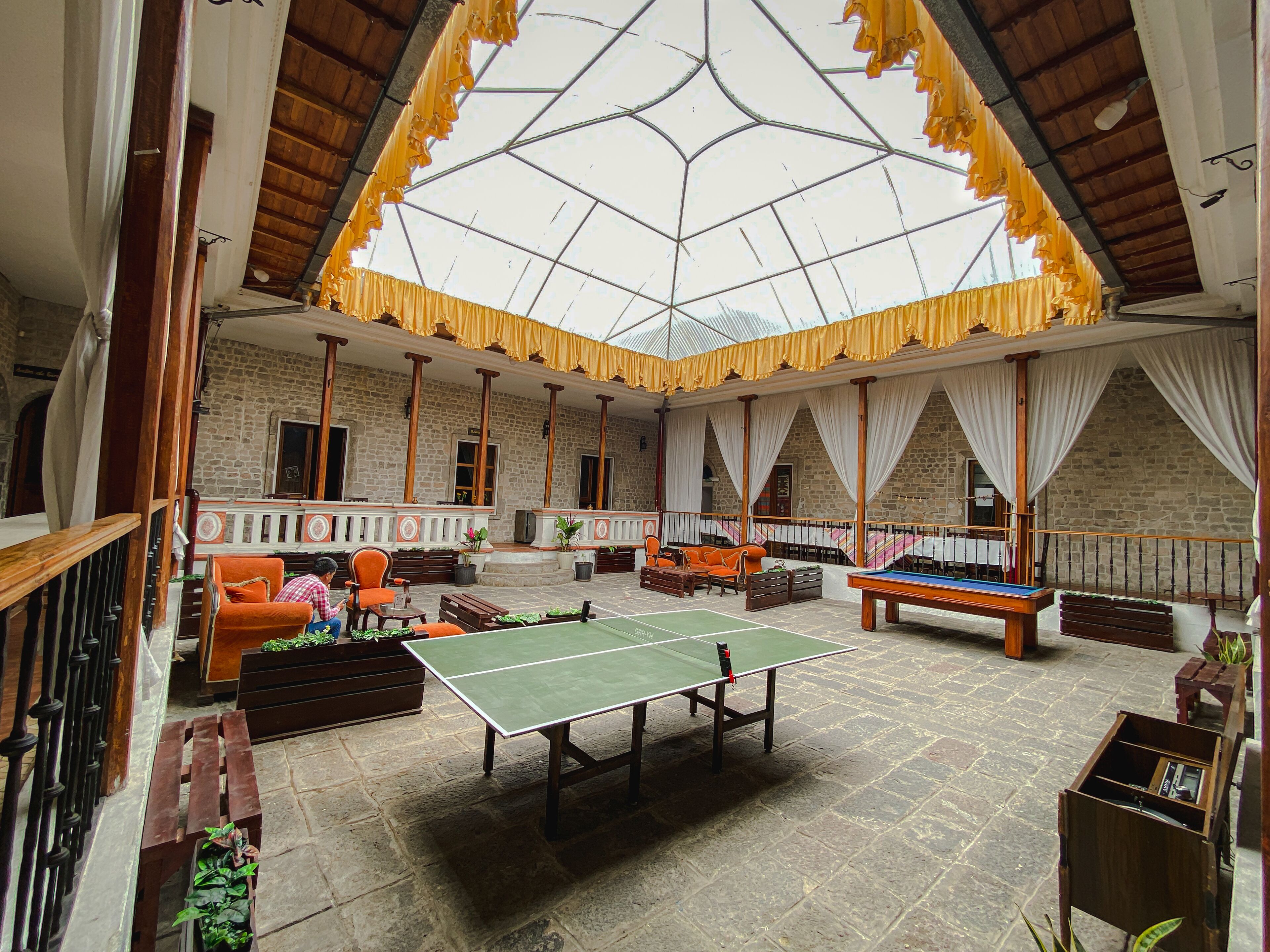 Um espaço amplo e interno com mesa de pingue-pongue, assentos e piso de pedra.