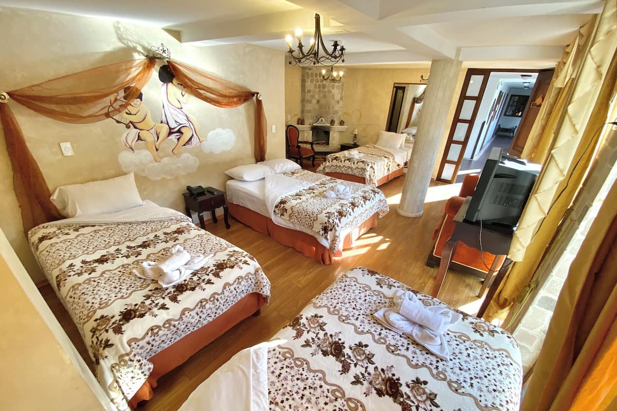 Habitación de hotel con tres camas, un candelabro, un televisor y un espejo.