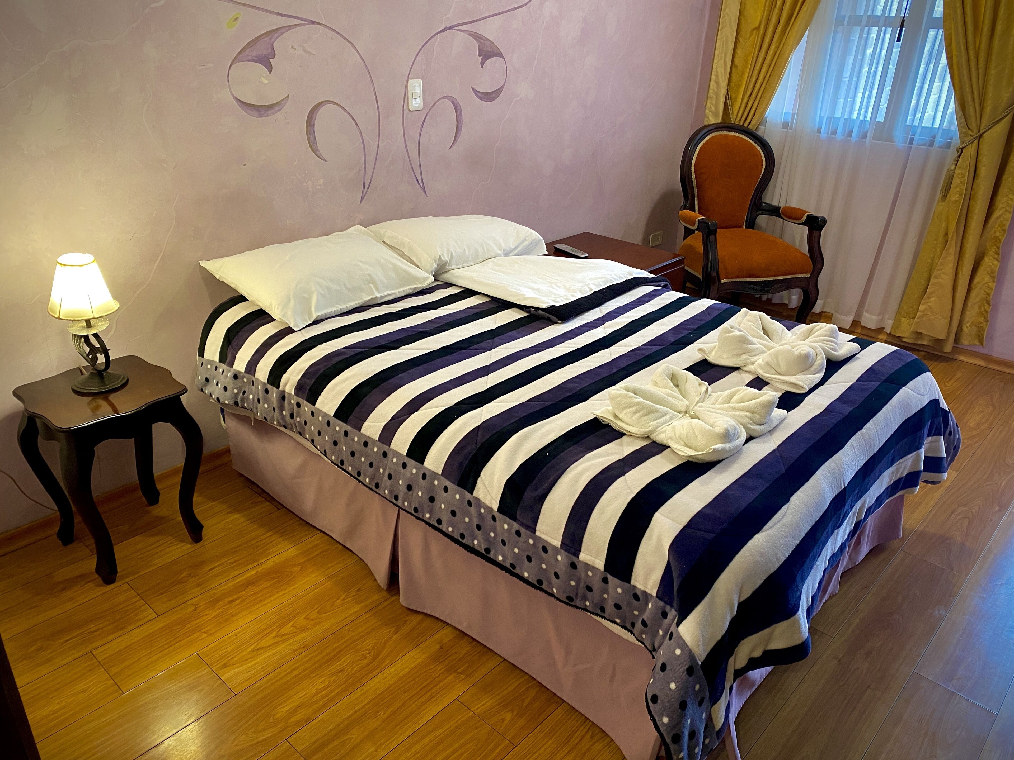Una cama bien hecha con ropa de cama a rayas y dos toallas.